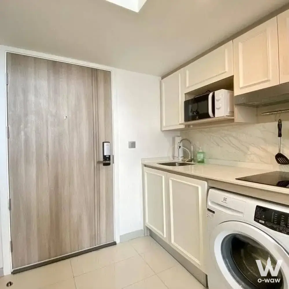 Compact kitchenette in a 1-bed condo at KnightsBridge Prime Sathon with cream cabinetry and induction cooktop