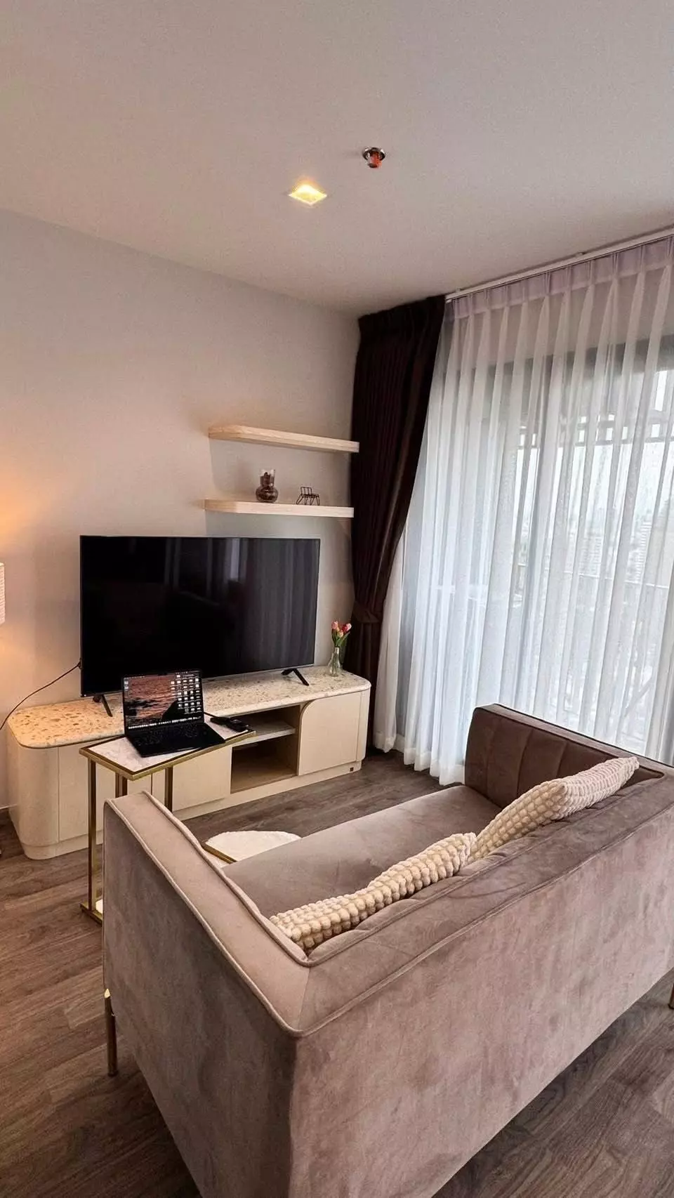 Living room with taupe velvet sofa and gold accents in 1-bed condo for rent at Life Ladprao Valley