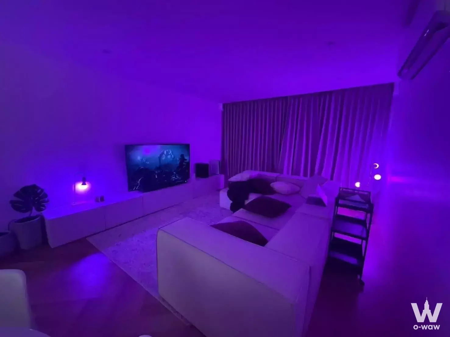 Living room with L-shaped sofa and TV under purple ambient lighting in Supalai Place Sukhumvit 39