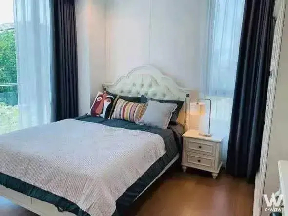 Bright bedroom in a Supalai Oriental Sukhumvit 39 condo featuring a tufted queen bed and hardwood floors