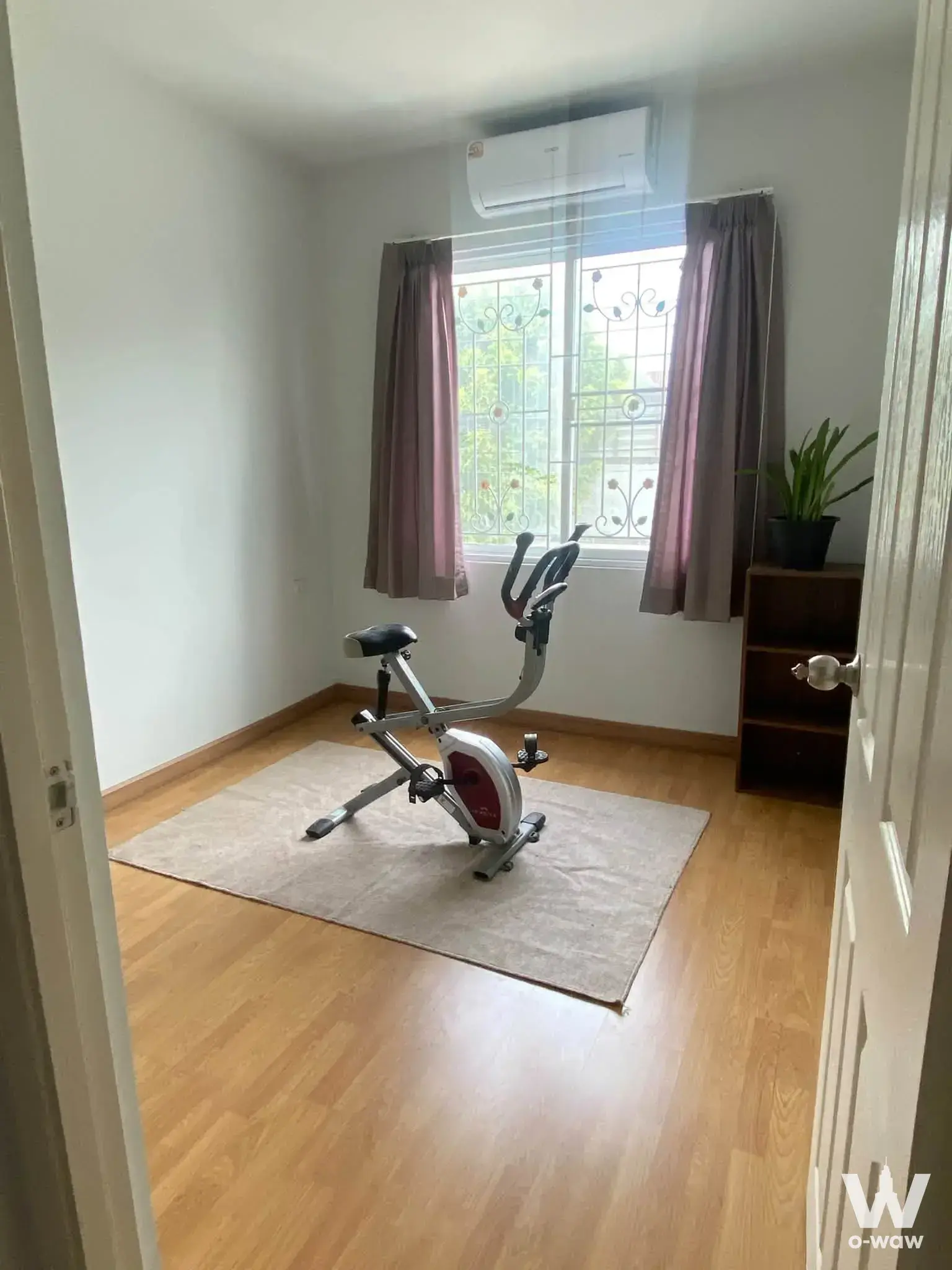 Home gym room with recumbent exercise bike, large window with security grille, and potted plant in a 3-bed townhouse for