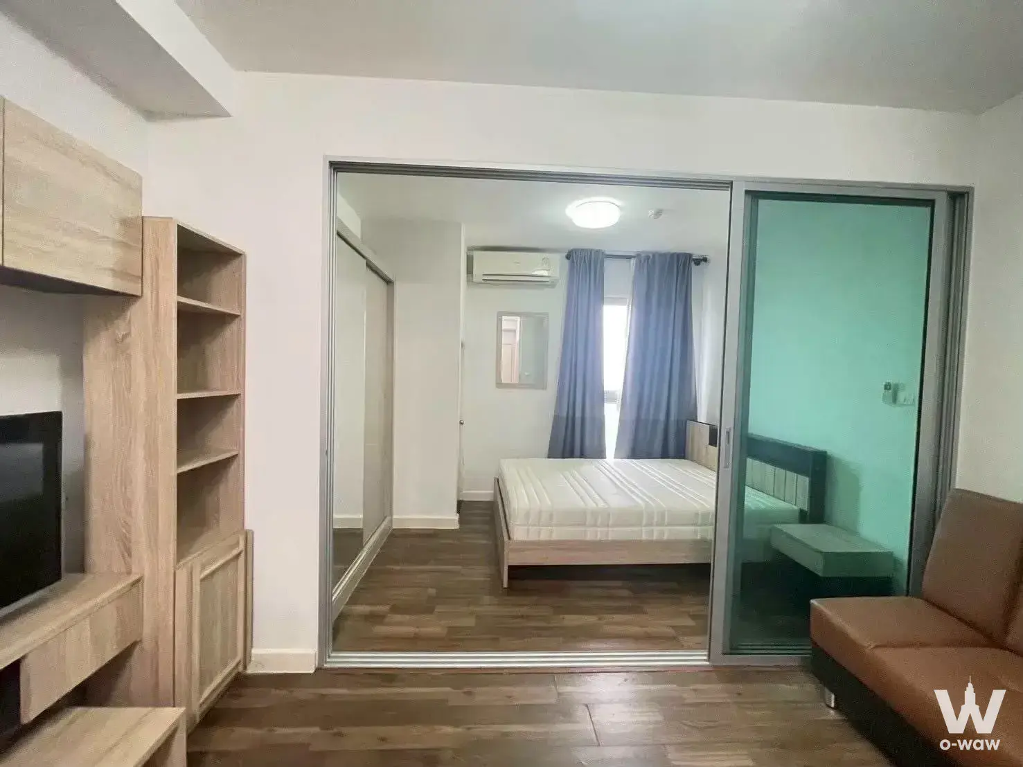 A Space Me Bangna studio apartment with dark wood floors, sliding glass partition, and open layout