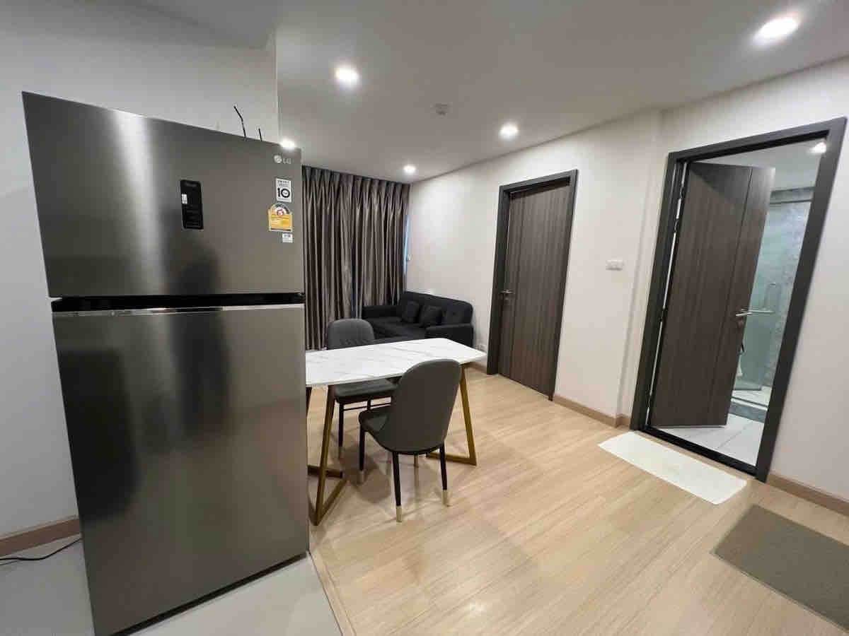 Open-plan living area with marble dining table and grey sofa in Supalai Prime Rama 9 condo