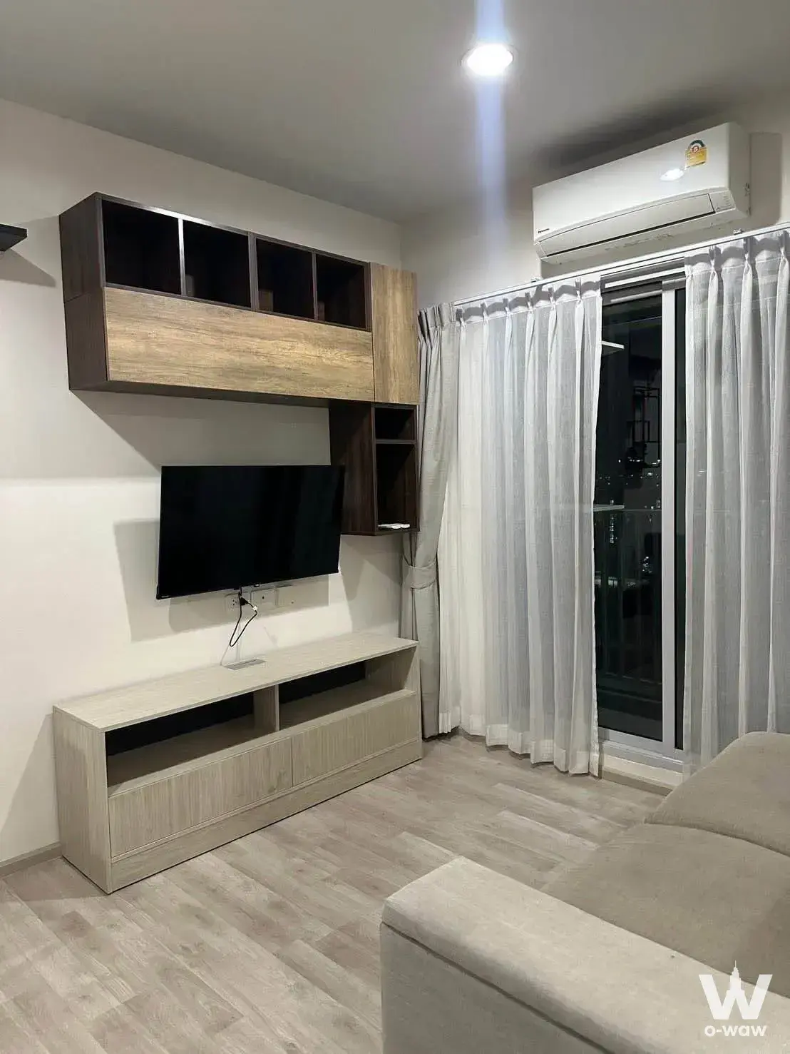Minimalist beige sofa and balcony doors in Niche MONO Ramkhamhaeng 1-bed condo living area