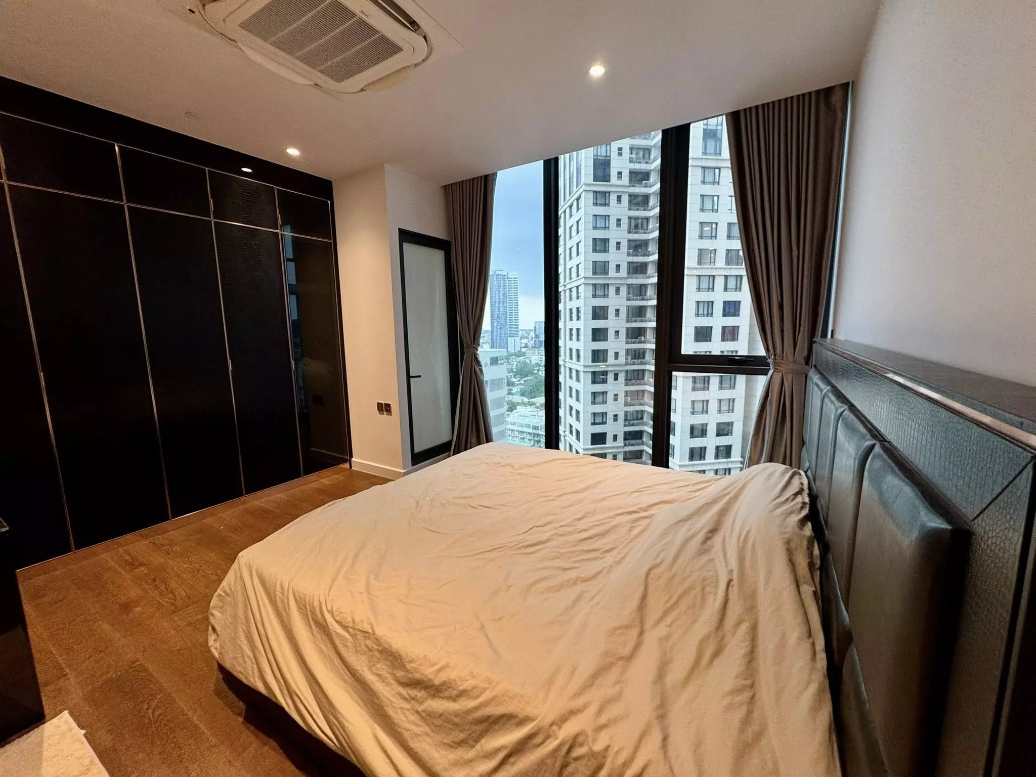 Bedroom in Supalai Icon Sathorn condo with black wardrobe and city view windows