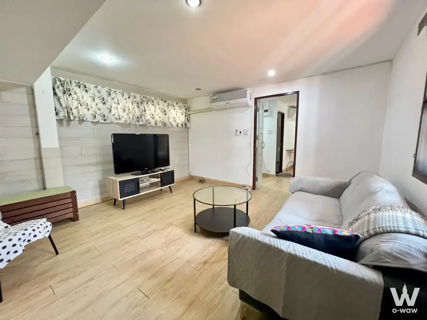 Furnished living room in a 4-bed Sammakon Village rental with light wood floors and a white brick accent wall