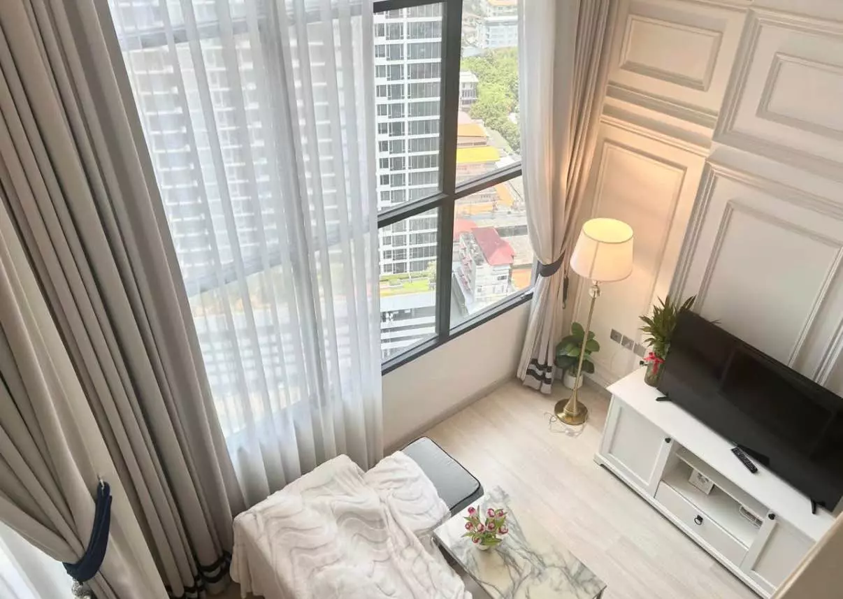 Living room in KnightsBridge Prime Sathon with floor-to-ceiling windows, urban view, grey chaise lounge, and marble coffee