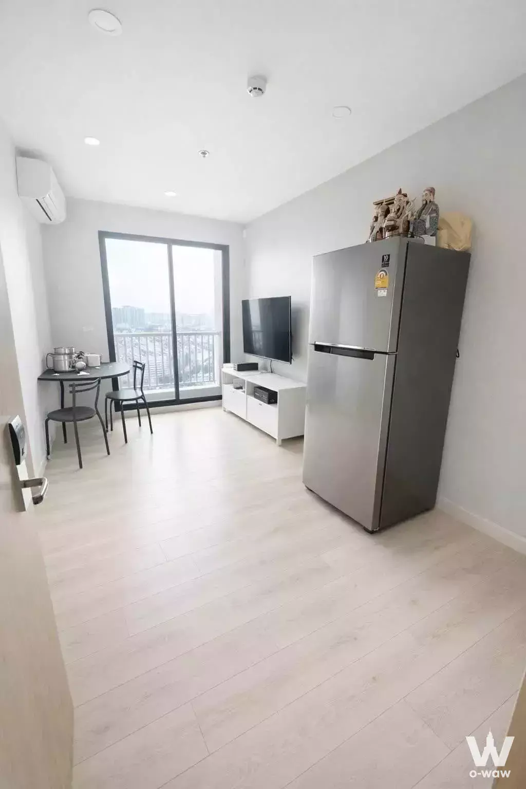 Open-plan living space with floor-to-ceiling glass doors, balcony view, and media console in Brix Condominium Charan 64