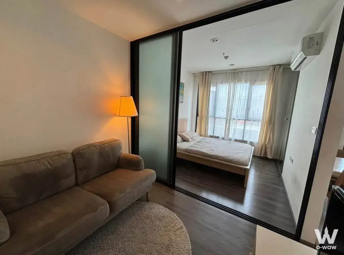 1-bed condo for rent in The Base Park East Sukhumvit 77 with taupe sofa and frosted glass bedroom partition