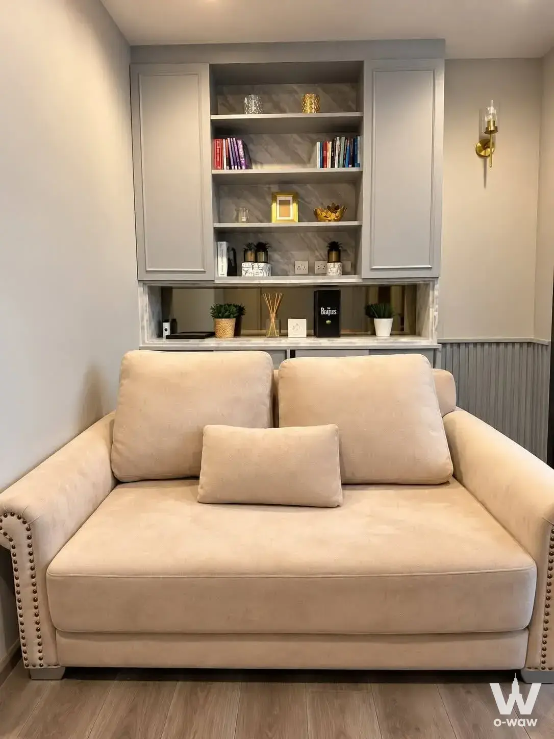 Beige sofa with brass trim and grey built-in shelving in The Politan Aqua
