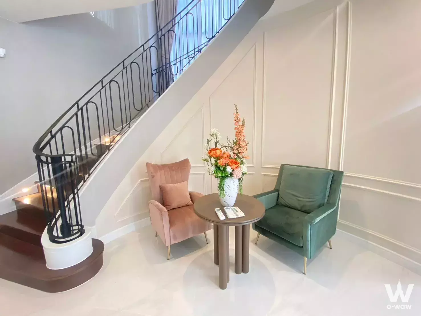 High-ceilinged foyer with curved staircase and velvet armchairs in 5-bed Narasiri house