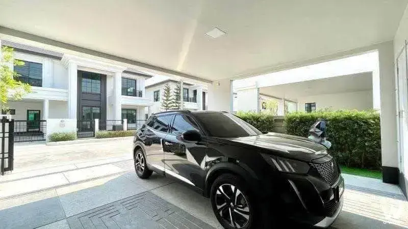 Covered driveway of Setthasiri Bangna-Suvarnabhumi townhouse with parked SUV