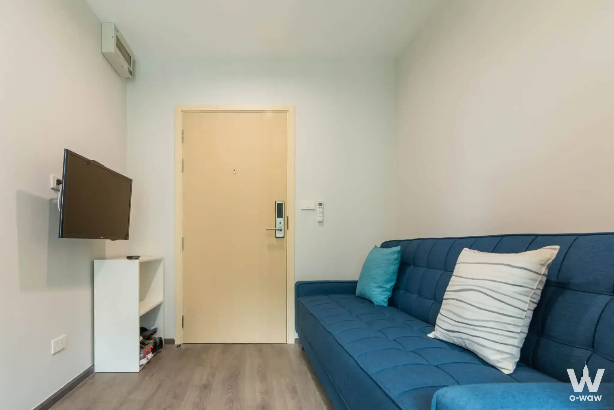 Rich Park Triple Station one-bed condo living room with blue tufted sofa and TV