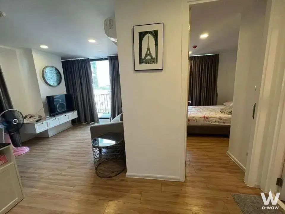 Grey sofa and TV in living area of 1-bed condo for rent at Notting Hill Charoen Krung 93