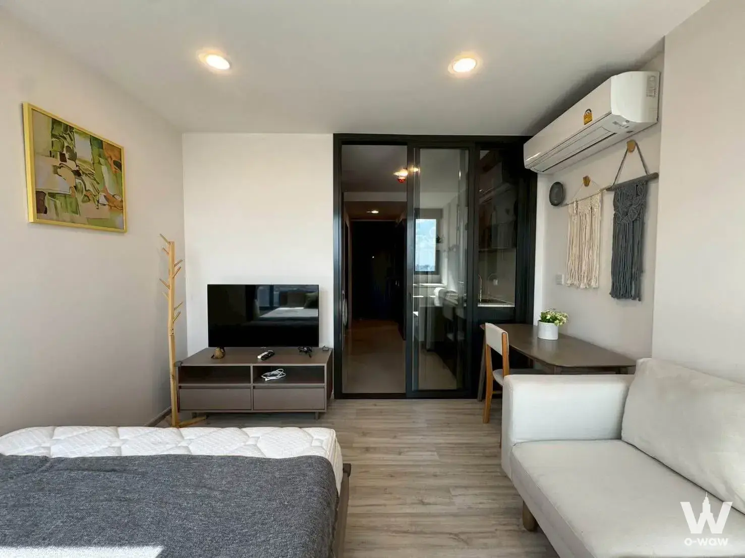 Modern 1-bed condo living area in XT Huai Khwang with wood floors, sofa, and TV console
