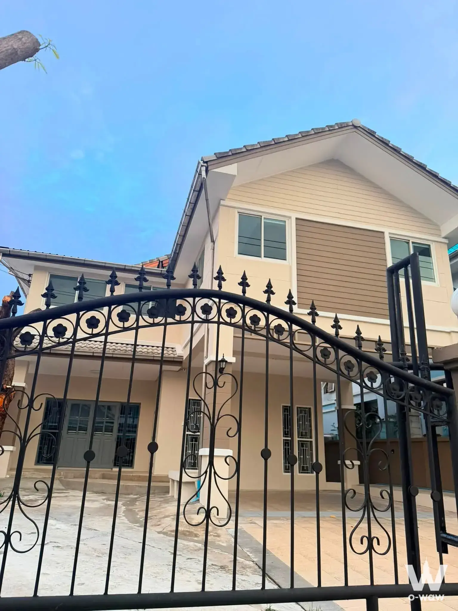Panason Garden Home 7 6-bed house exterior with beige siding, arched gate, and blue sky