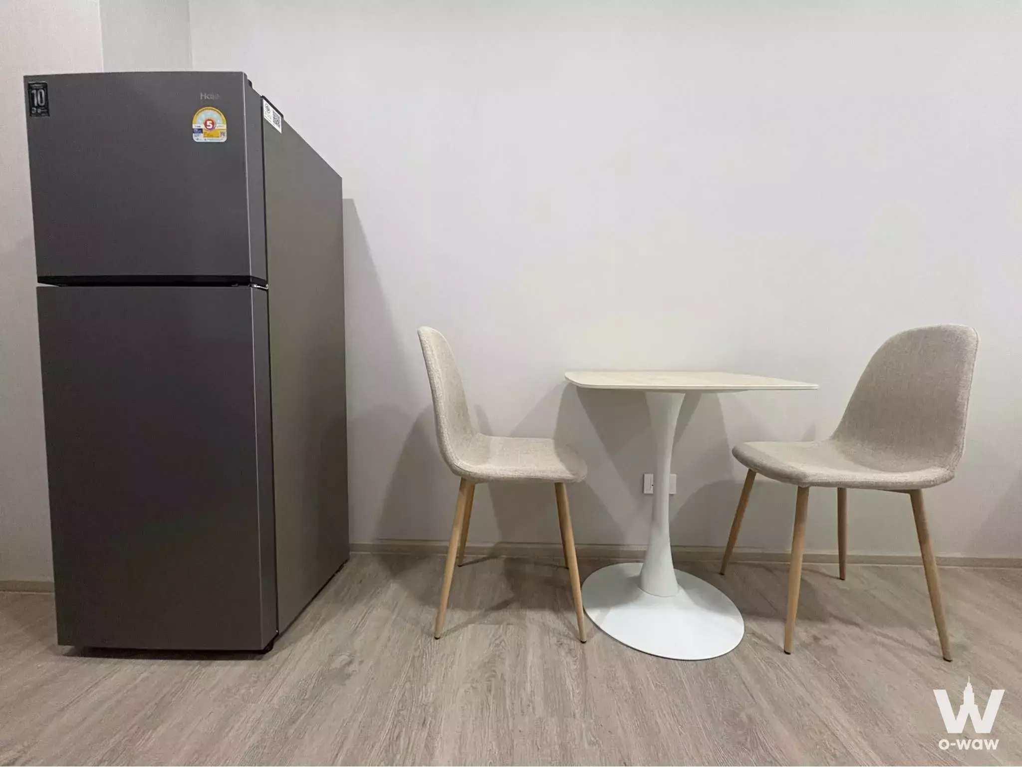 Minimalist dining area in Supalai Sense Srinakarin condo with round table and grey fridge
