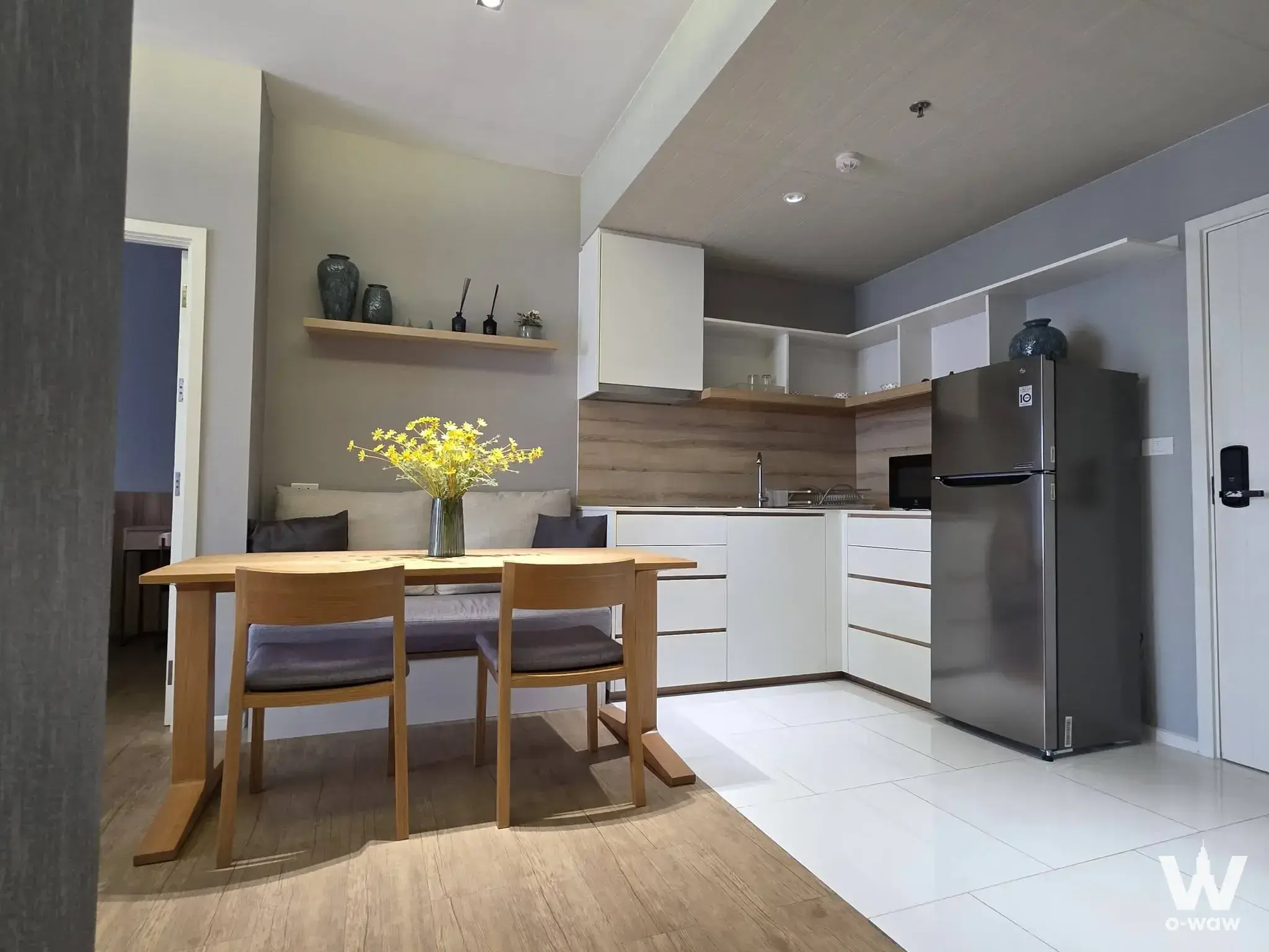 Open-plan kitchen and dining area in Triple Y Residence with light wood table and white matte cabinets