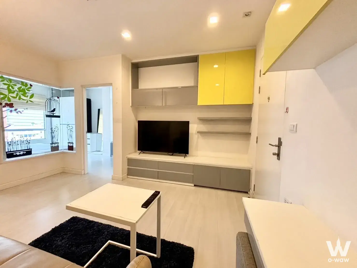 Living room with yellow glossy cabinets and grey entertainment unit in a 1-bed condo for sale at The Room Ratchada-Ladprao