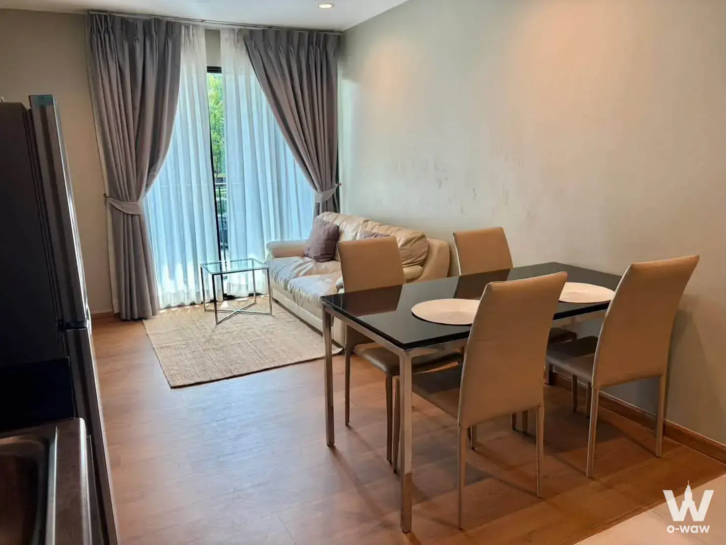 Living and dining area with beige sofa and glass table for a 2-bed condo in THE BASE Park West