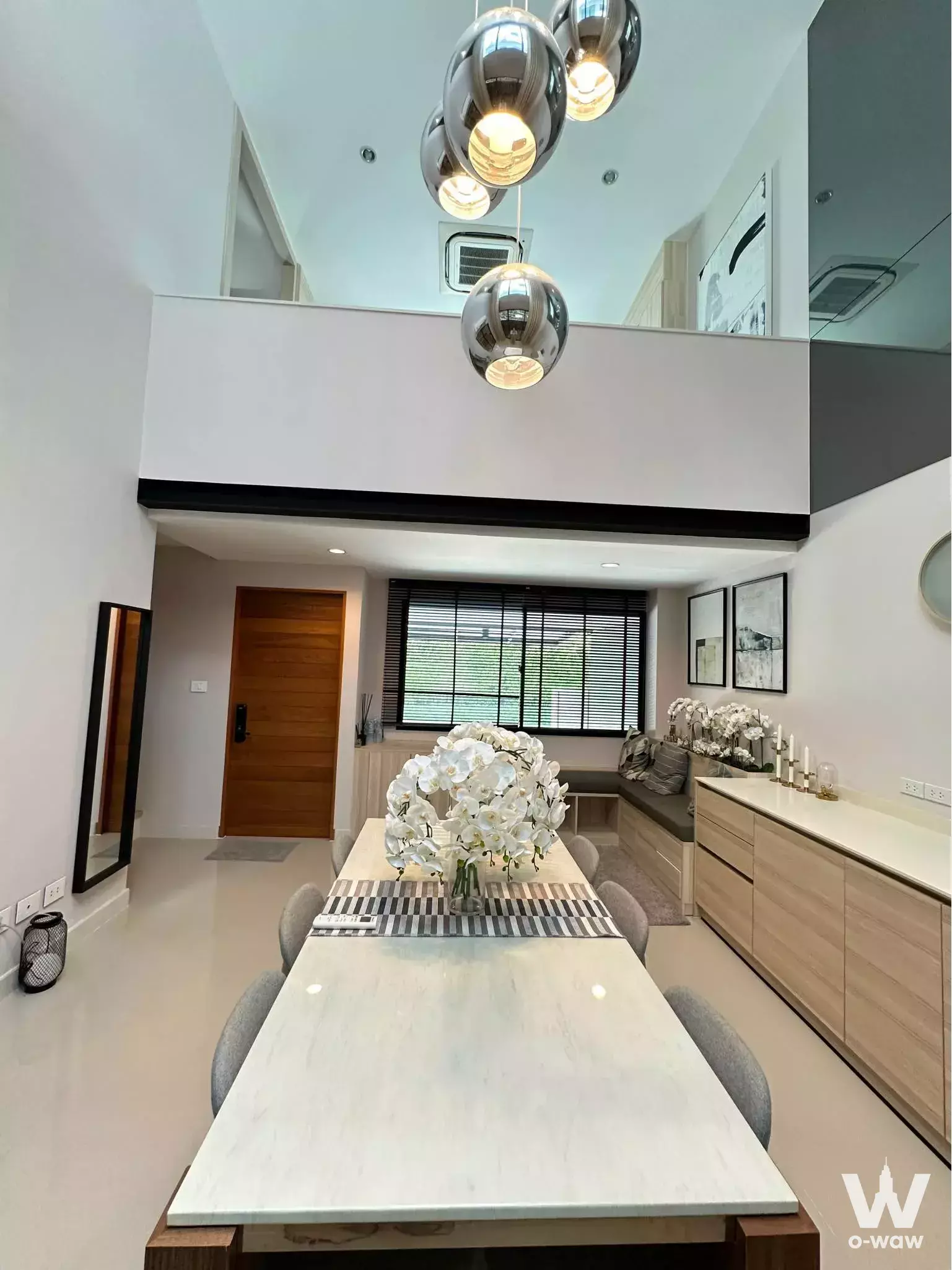 High-ceiling dining area with marble table and chrome pendants in 3-bed townhouse for sale at Nirvana Define Rama 9