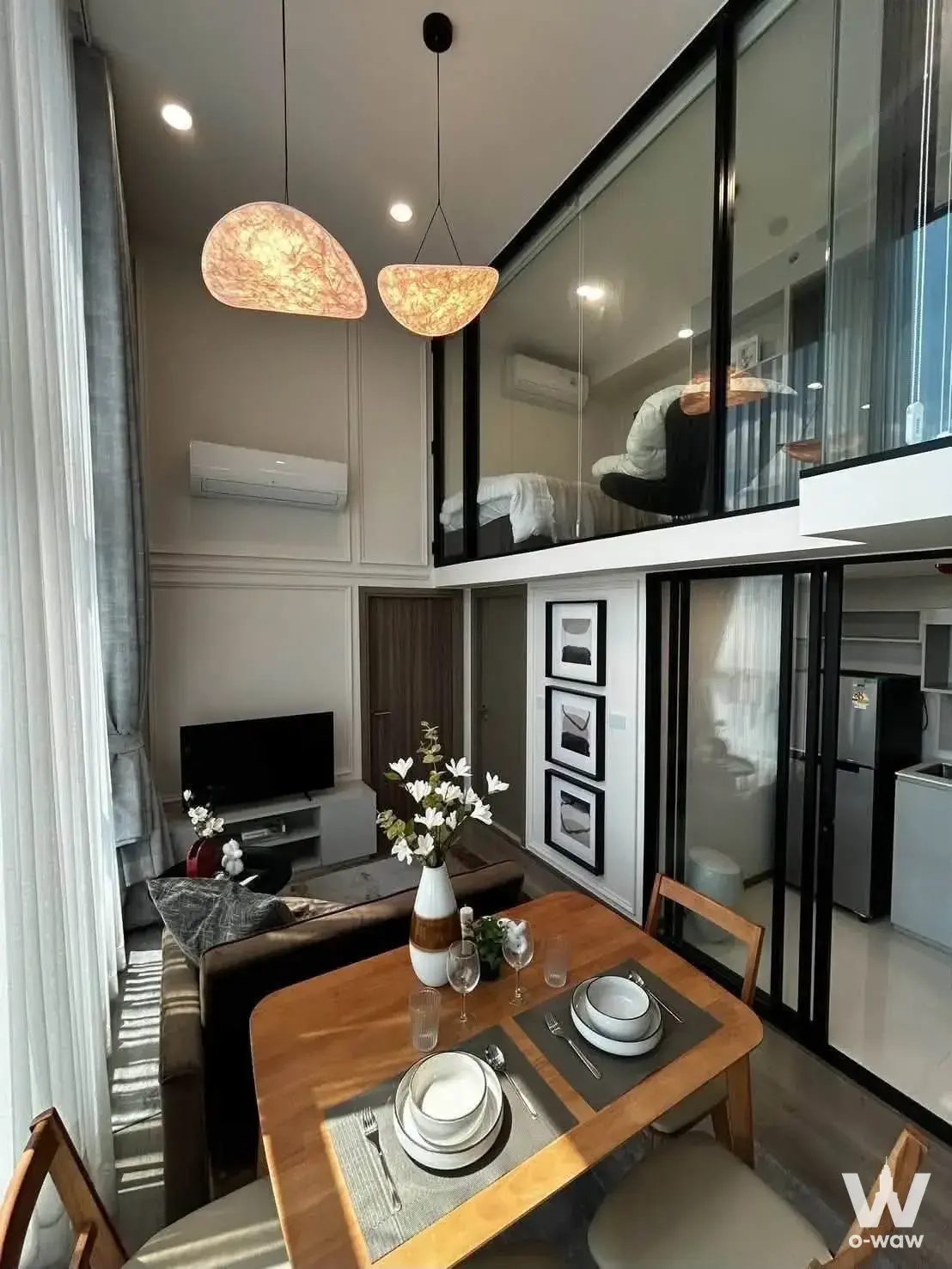 Double-height loft interior in a 2-bed KnightsBridge Space condo showing dining area and mezzanine bedroom