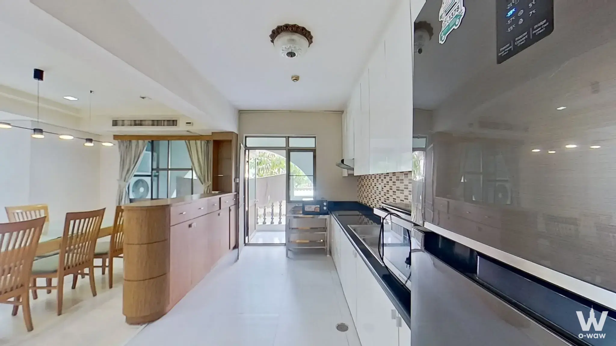 3-bed Royal Castle condo dining area with wood table, glossy white kitchen cabinets, and balcony access