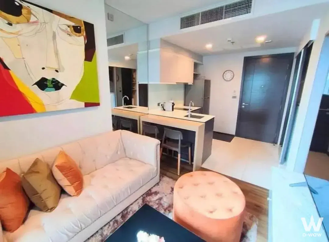 Open-plan living room with cream sofa and kitchen island in a CEIL By Sansiri condo for rent