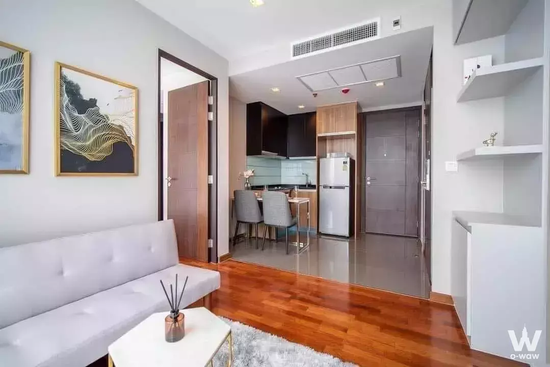 Studio apartment in WISH Signature Midtown Siam with white tufted sofa, wood flooring, and open kitchenette
