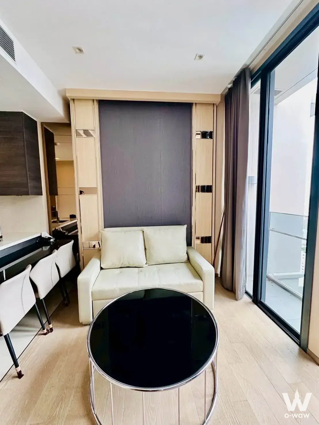 Studio living area in THE ESSE ASOKE condo featuring cream sofa and built-in Murphy bed unit
