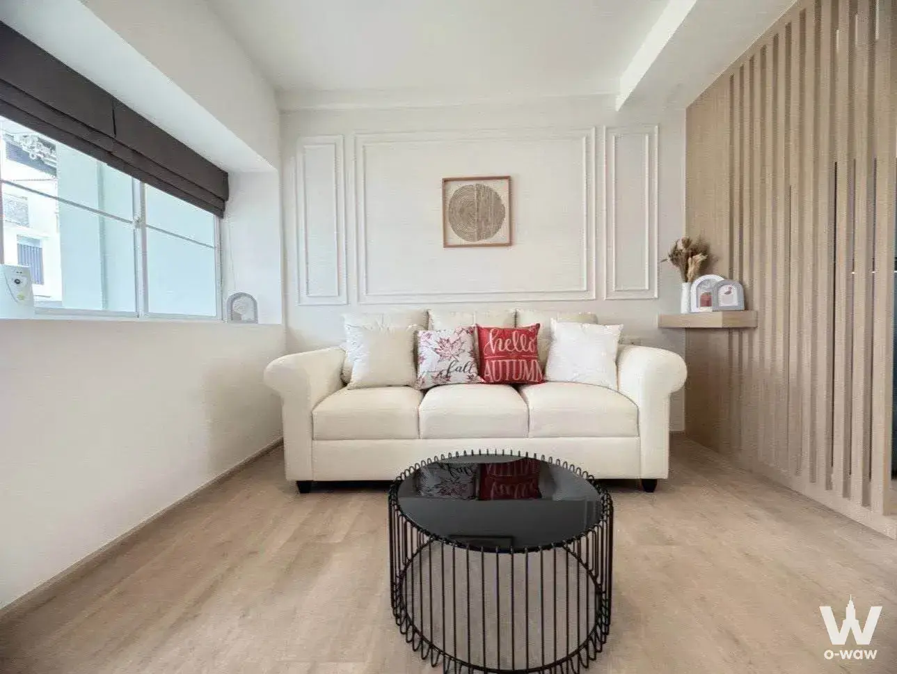 This living room in a 2-bed townhouse for rent at Indy 2 Bangna-Ramkhamhaeng 2 has a white leather sofa and light wood slats