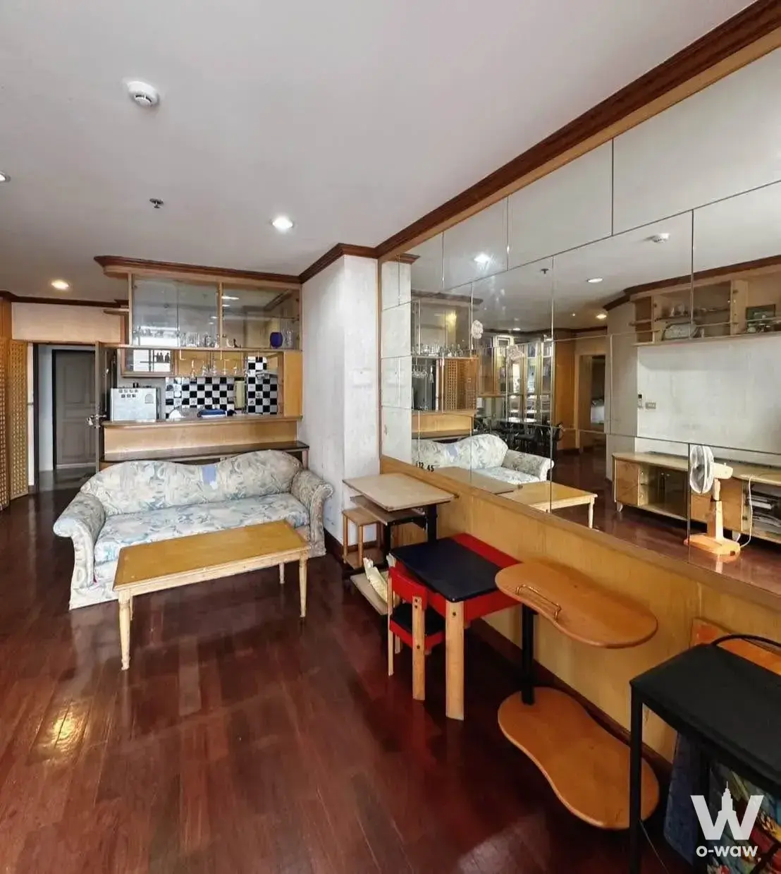 Retro living room in Pathum Wan Resort with floral sofa, checkerboard bar, and dark wood floors