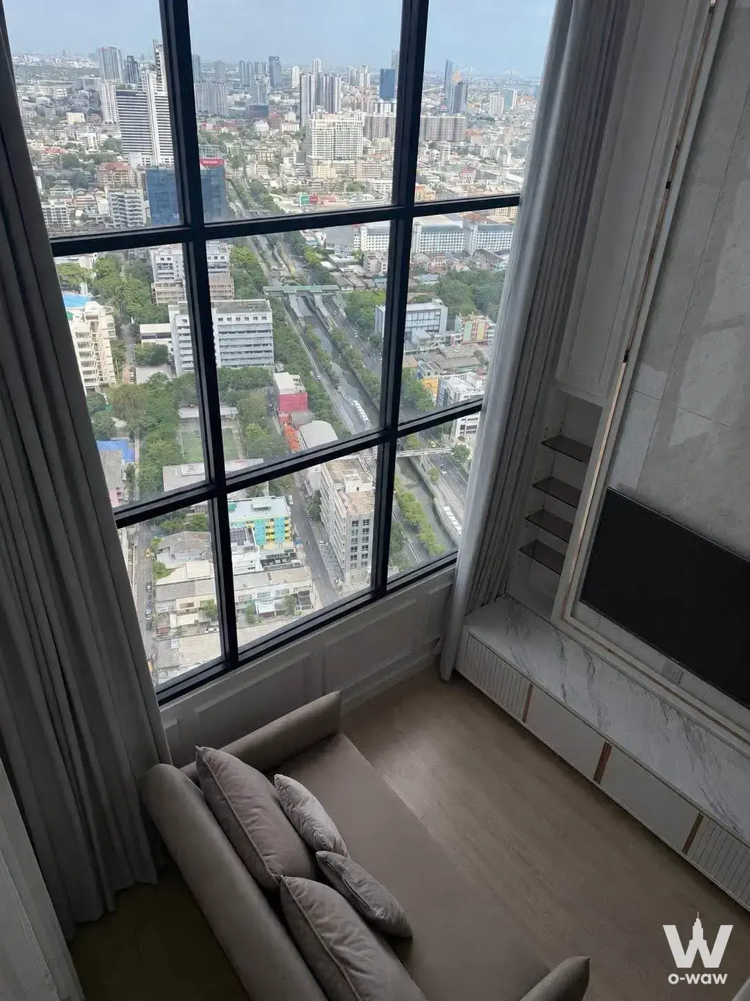KnightsBridge Prime Sathon living room with city view, beige sofa, and marble TV unit
