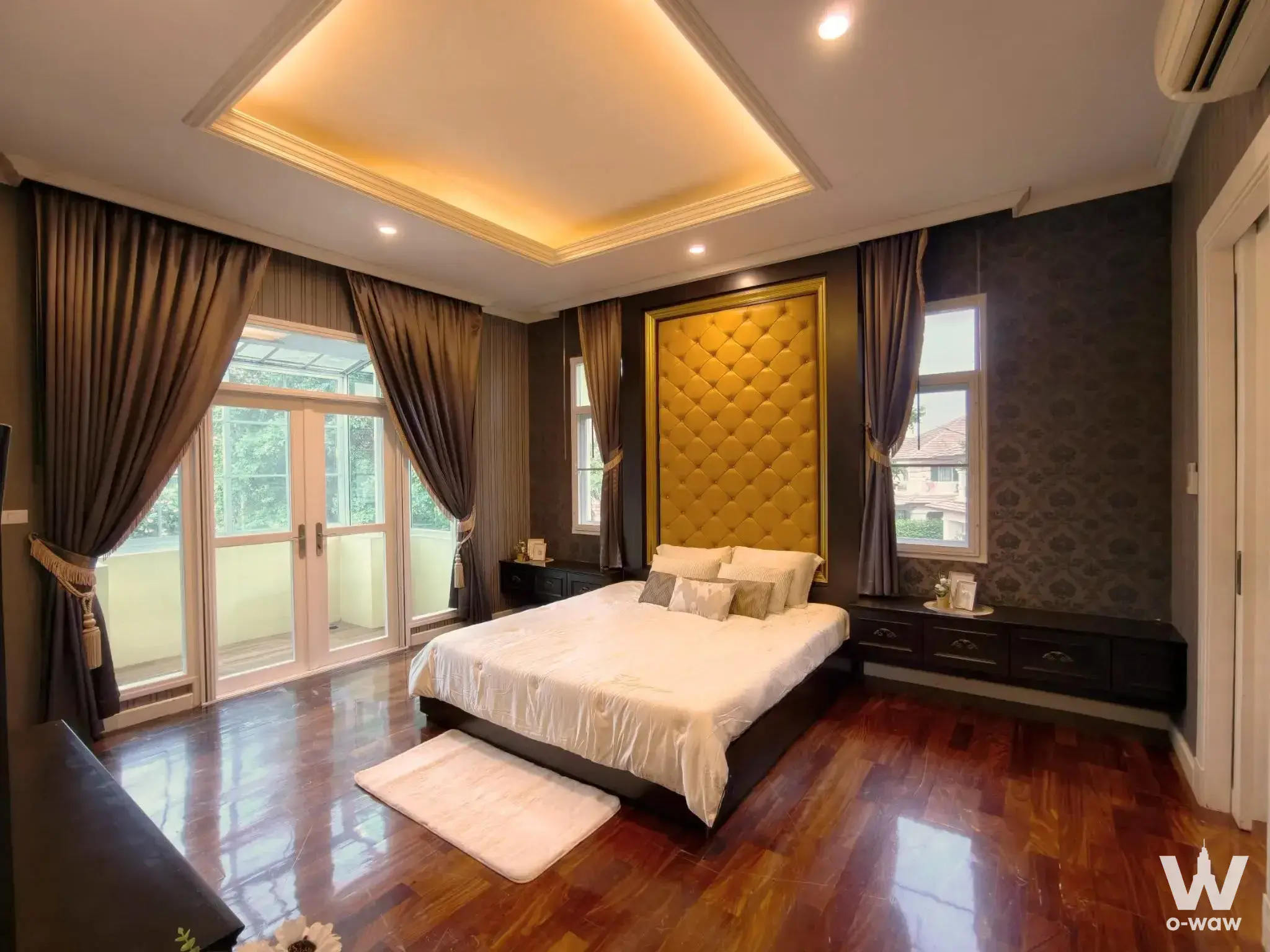 Master bedroom in The Grand Rama 2 house with gold tufted headboard and dark grey damask walls