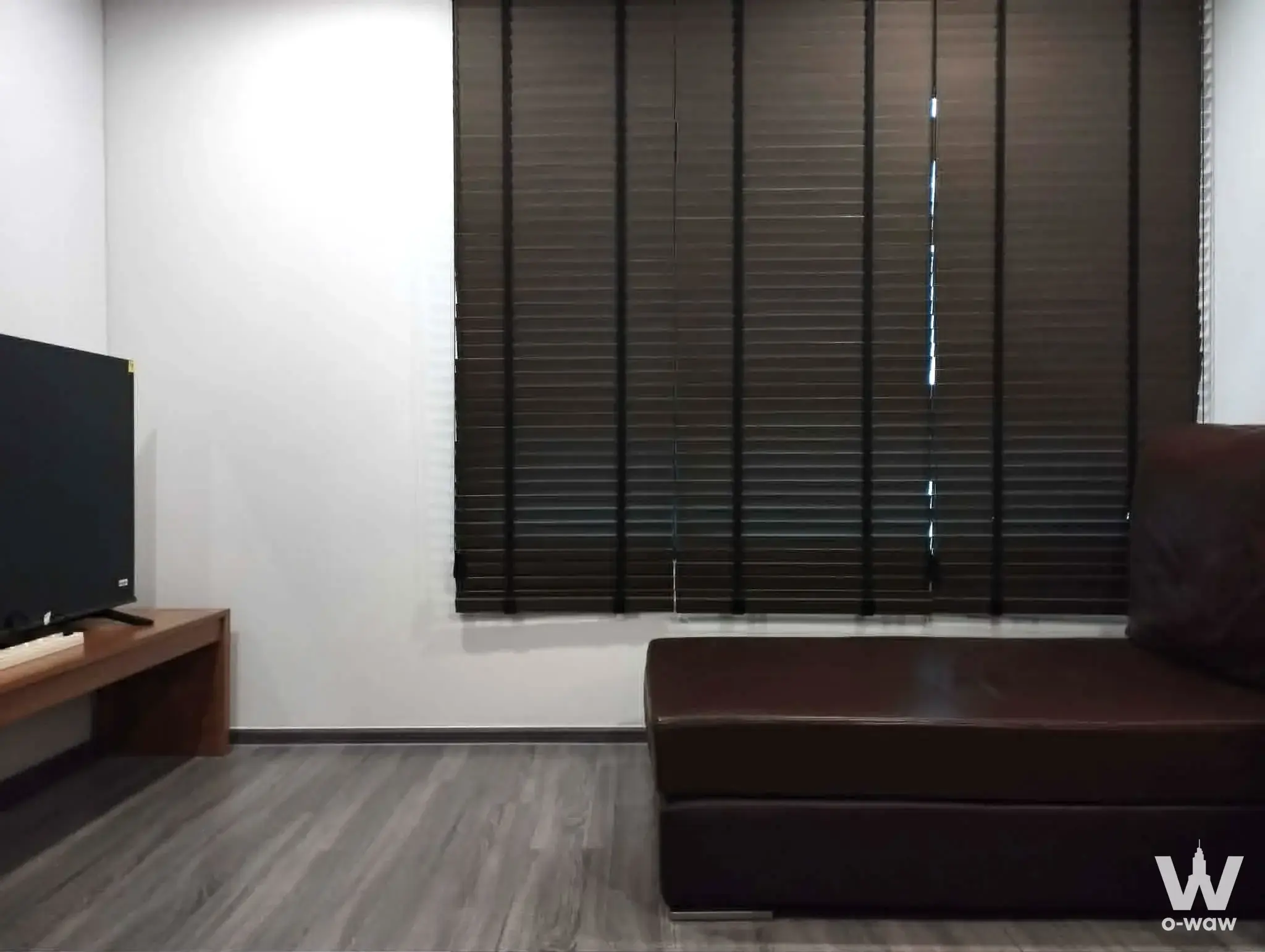 Minimalist living area in Ideo Ramkhamhaeng Lamsali with leather chaise and TV console