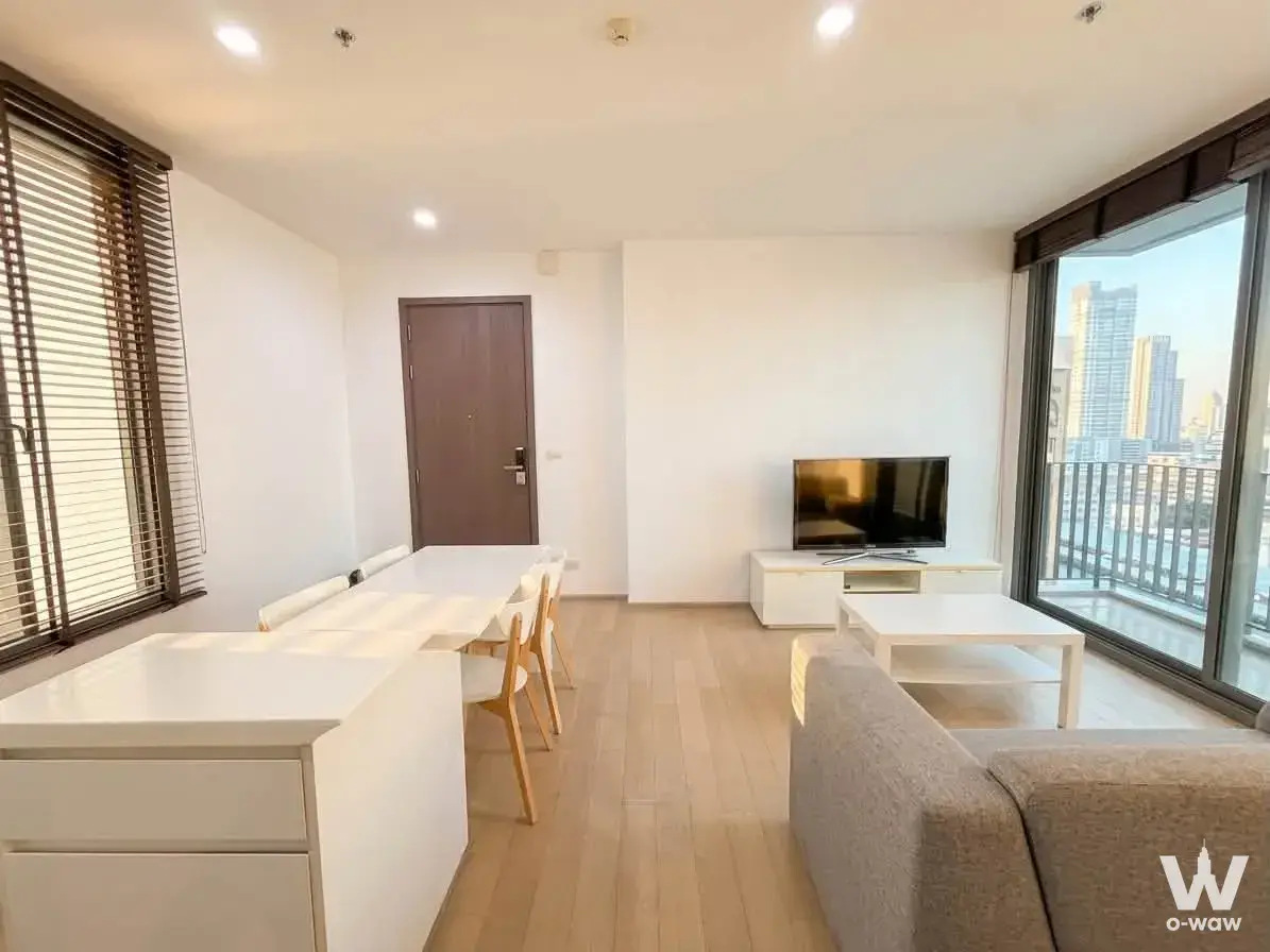 Modern 1-bed condo living area in PYNE by Sansiri featuring oak flooring, dining set, and river view