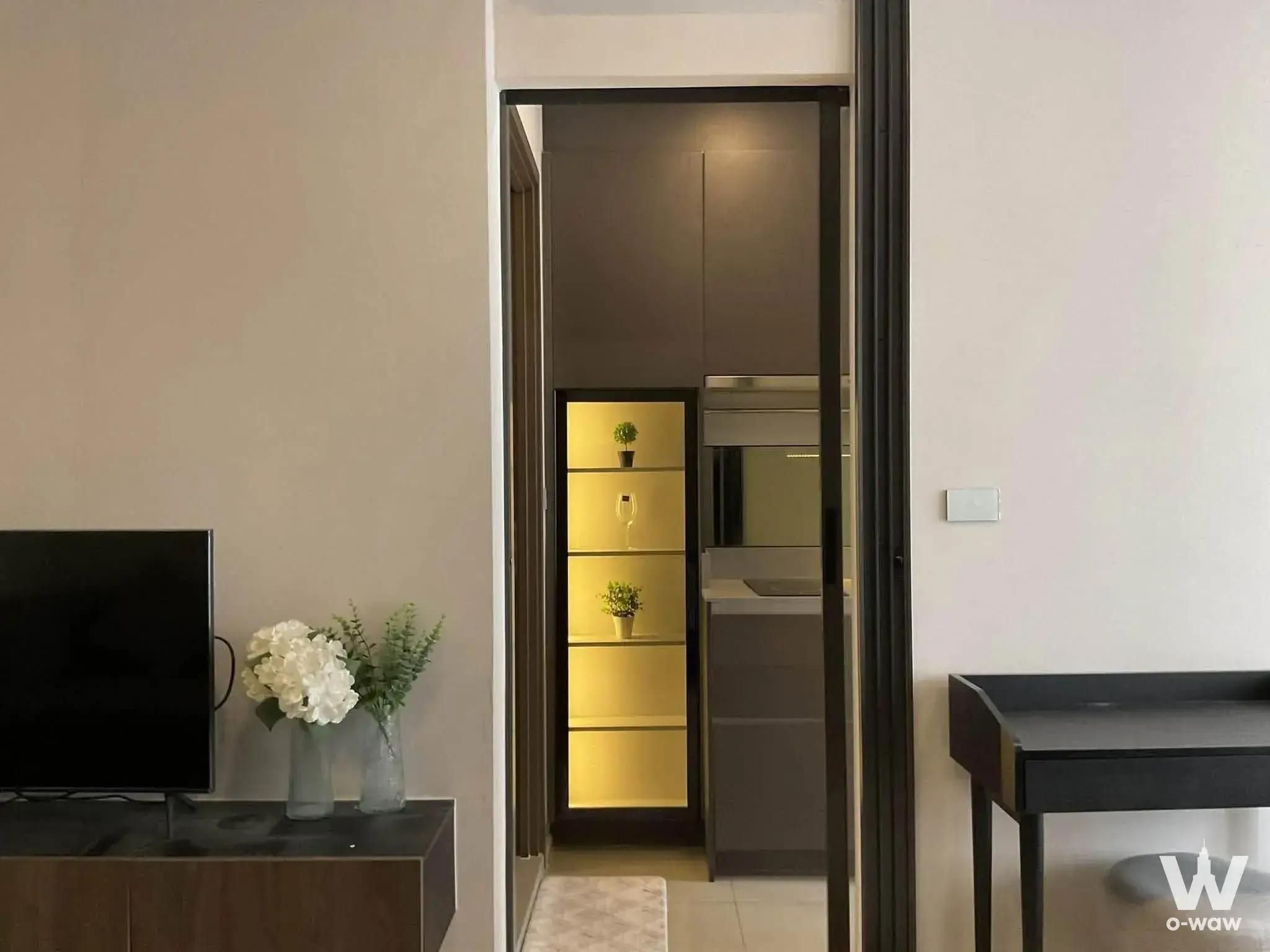 Modern living room in a 1-bed condo for rent at The Privacy Jatujak featuring dark wood media console and illuminated