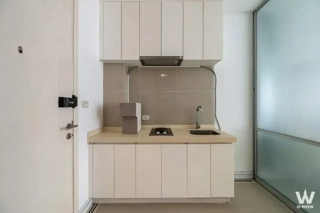 Compact kitchenette in TC Green Rama 9 condo with white cabinets and stainless steel appliances