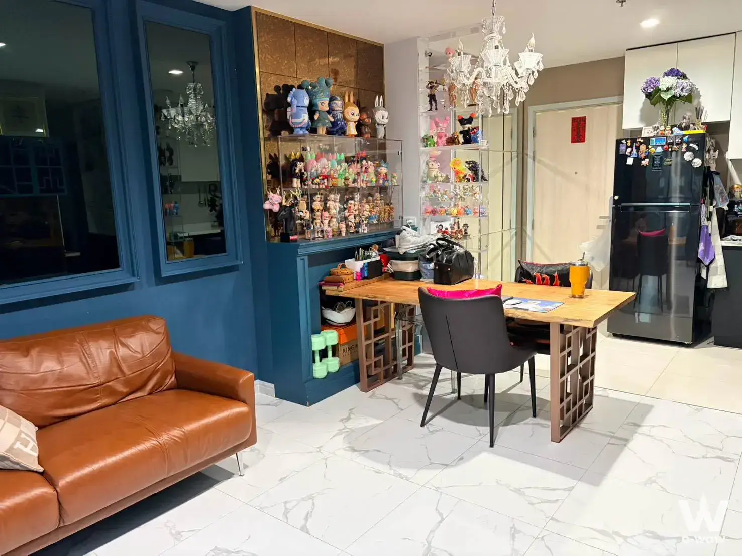 Open-plan living area in a Life One Wireless 2-bed condo with leather sofa and anime figurine display cases