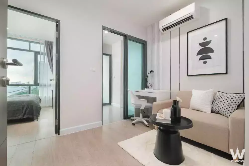 Open-plan studio with beige sofa, workspace, and city view in Metro Sky Prachachuen condo for sale