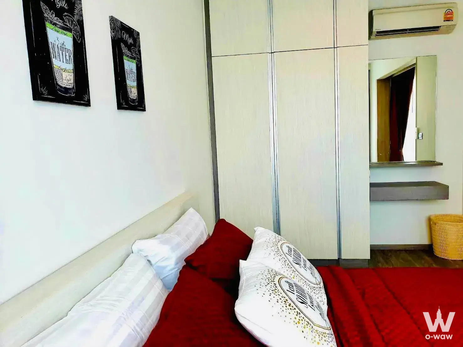 Modern bedroom with red bedding, light wood headboard, and floor-to-ceiling wardrobe