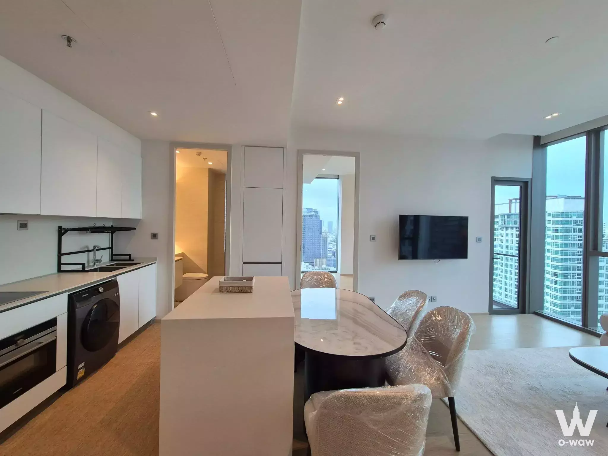 Open-plan living area with marble dining table and city views in 2-bed Thonglor condo