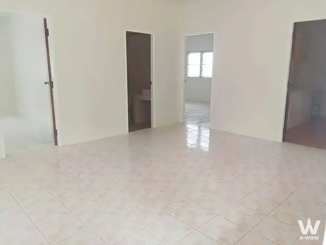 Empty unfurnished living room with glossy tile floors and multiple doorways in 2-bed commercial unit at Park Village Rama 2