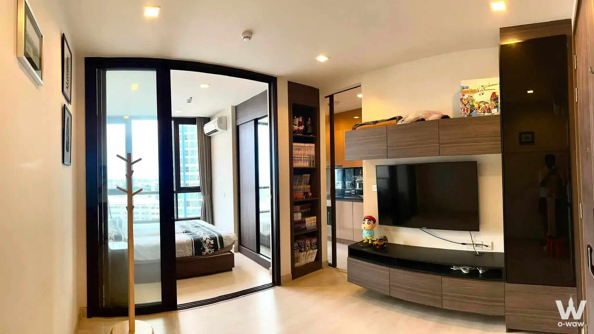 Open-plan living space in a THE LINE Sukhumvit 71 condo showing dark wood console and bedroom view