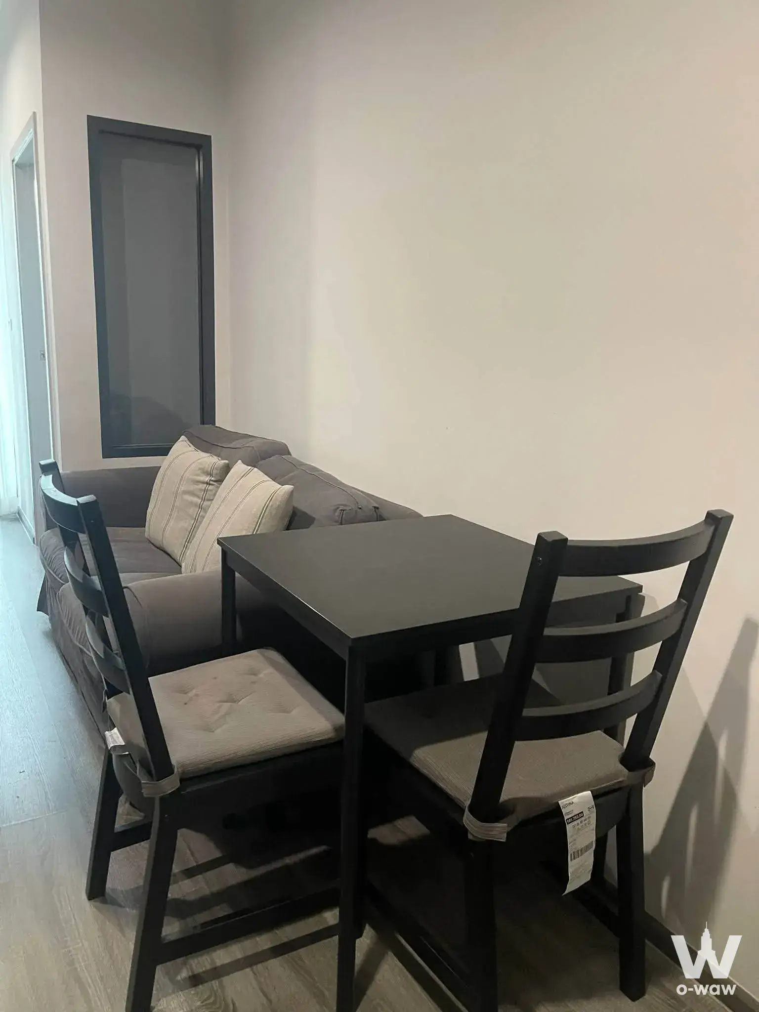 Dining corner in an IDEO Chula-Sam Yan condo featuring a dark wood table, ladder-back chairs, and a grey fabric sofa