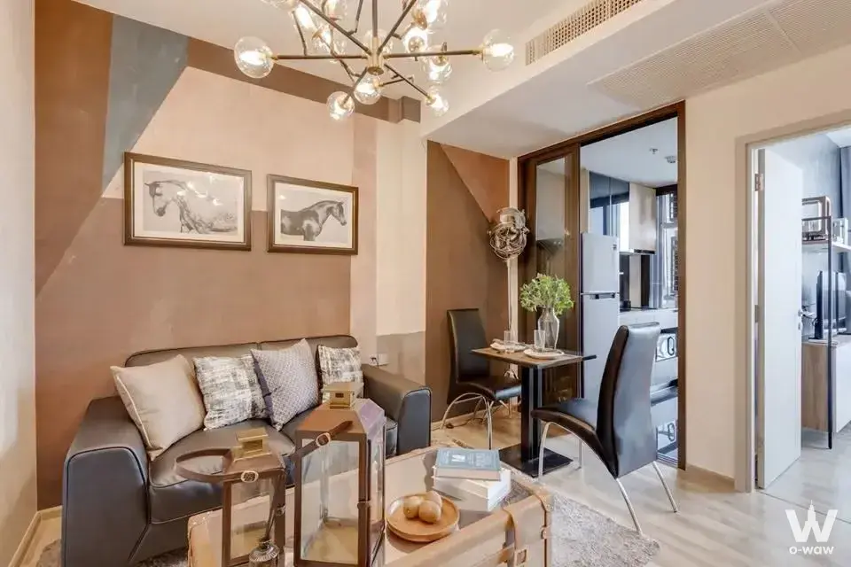 Living area in THE LINE Chatuchak-Mo Chit condo for rent with geometric accent wall, leather sofa, and dining set