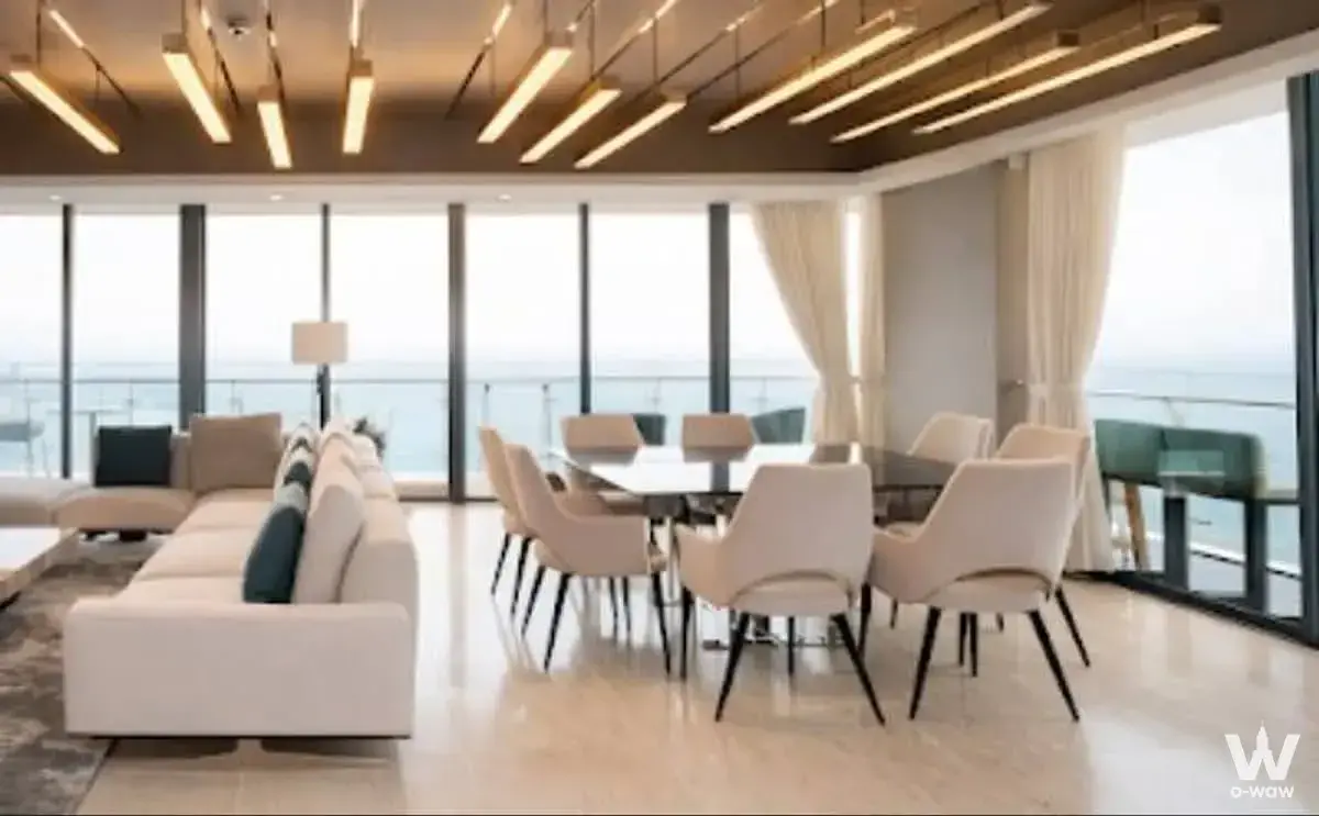 Spacious living area with sectional sofa, dining set, and ocean views in The Pano condo