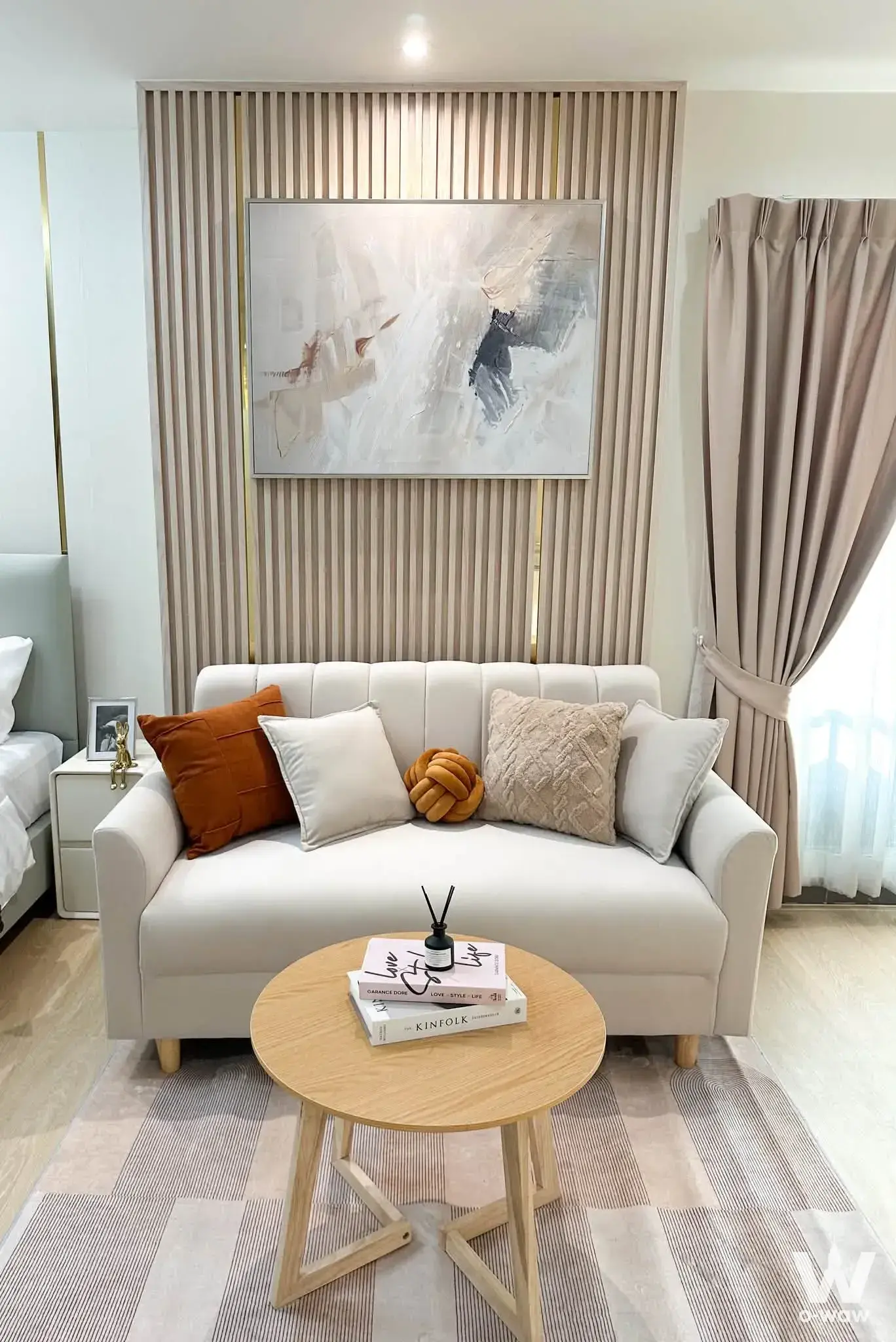 Regent Home Bangson 27 living area with cream sofa, wood slat wall, and abstract art