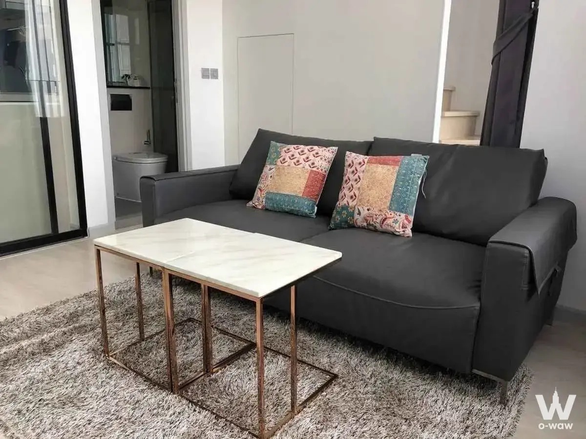 Modern living room with charcoal sofa, copper coffee table, and grey shag rug near glass balcony doors