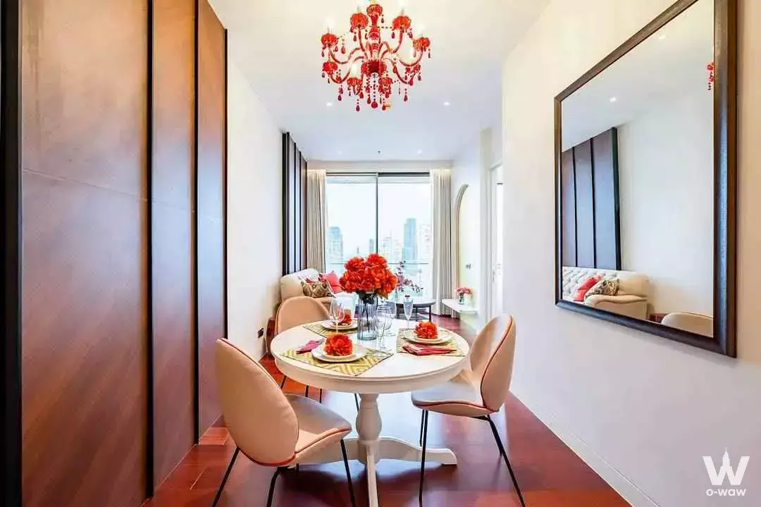 Dining area in KHUN by YOO condo with round table, red chandelier, and city view